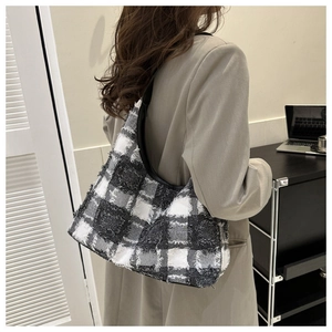 Gros plan d'un sac d'épaule en tweed à damier noir et blanc avec bandoulière en cuir et franges