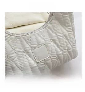 Détail du sac blanc froncé et matelassé avec écusson logo en cuir Akobia People