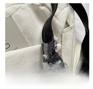 Gros plan du cabas en tweed noir et blanc avec détails de franges et bandoulière en cuir