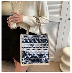 Detail einer Canvas-Handtasche mit geometrischem Muster und strukturierten Griffen