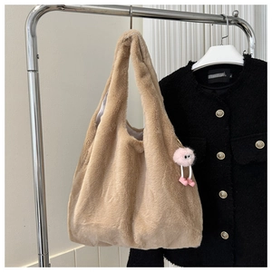 Detail view of large light brown plush tote bag with a pink fluffy monster charm
