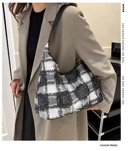 Gros plan sur le sac cabas en tweed écossais noir et blanc avec détails de franges sur le modèle