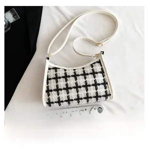 Close-up of checkered tweed shoulder bag with white leather trim and gold hardware details