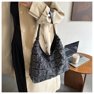 Détail du sac hobo à franges noires porté par un mannequin dans un bureau moderne