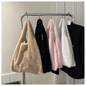 Detailed display of plush shoulder bags in khaki, black, pink and white hanging on a rack