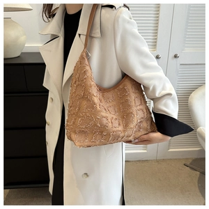 Détail du sac cabas à carreaux kaki avec franges sur un trench-coat blanc élégant