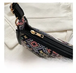 Detail view showing the smooth gold metal zipper on ethnic woven crossbody bag