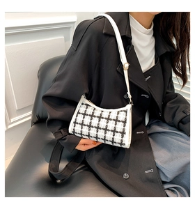 Detailed close-up of a black and white tweed plaid underarm bag with white leather trim