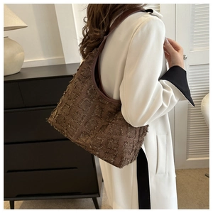 Détail du sac à bandoulière vintage marron à carreaux porté avec un trench-coat d'automne élégant