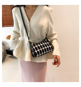 Chic black and white checkered tweed baguette bag shown worn on a shoulder