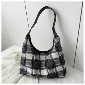 Détail d'un sac cabas en tweed noir et blanc avec bords effilochés et bandoulière en cuir