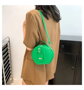 Dettaglio della borsa a tracolla tonda verde brillante con ecopelle trapuntata e hardware dorato