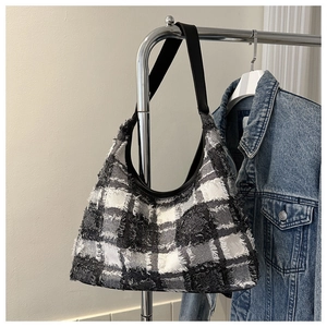 Détail du sac en tissu à carreaux avec franges sur un cintre en acier inox