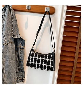 Detail of tweed checkered bag with gold zipper and strap against a home interior