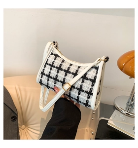 Detailed view of tweed plaid fabric and golden metal buckle on stylish shoulder bag