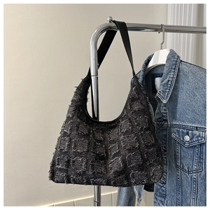 Détail du sac hobo avec tissu texturé gris foncé et bandoulière en cuir noir