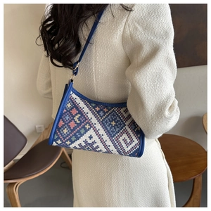 Close-up of bohemian woven shoulder bag with geometric patterns on a female model
