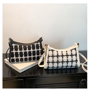 Close-up of black and white tweed baguette bags with elegant plaid texture and gold zipper