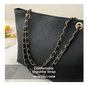Gros plan sur un sac noir à motif crocodile avec des détails de bandoulière chaîne dorée