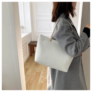 Détail du sac cabas blanc avec texture crocodile élégante et bandoulière en chaîne dorée