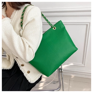 Détail d'un sac cabas vert en cuir gaufré avec une bandoulière chaîne dorée et cuir vert