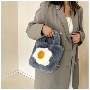 Close-up of blue plush crossbody bag with a fried egg design and gold chain strap