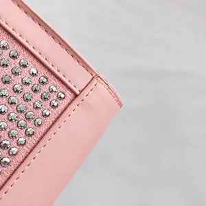 Close-up of pink leather handbag featuring sparkling silver rhinestones and premium stitching