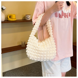 Dettaglio del tessuto bianco con texture a bolle su una borsa a spalla da donna