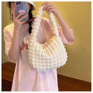 Dettaglio della borsa color crema con trama a bolle e finitura in tessuto popcorn