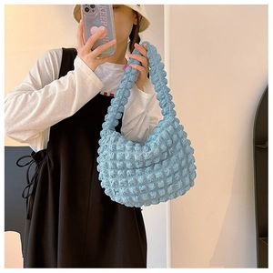 Dettaglio del tessuto azzurro con texture popcorn e struttura a nuvola della borsa