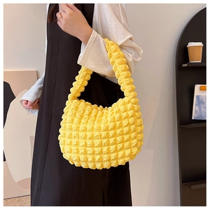 Dettaglio della borsa a mano giallo brillante con texture a bolle su una modella