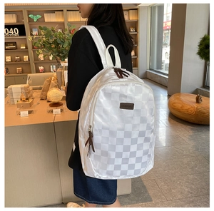 Close-up of white checkered pattern backpack with premium brown leather pullers and logo