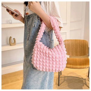 Vista dettagliata della borsa a spalla rosa con trama a bolle portata da una modella