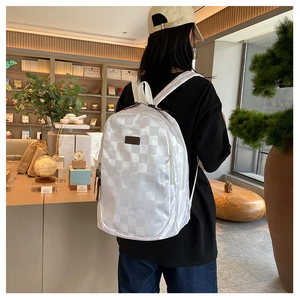 Detail of white checkered pattern backpack on model in a bookstore setting