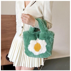 Detail of green faux fur crossbody bag with daisy motif and thin metal chain strap
