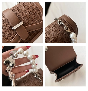 Detailweergave van bruine geweven mini tas met parel- en zilveren hartketting