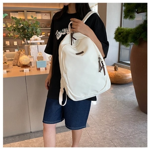 Detailed view of white minimalist backpack with leather zipper pulls and side pockets