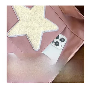 Detail of pink canvas tote showing a front pocket and cream plush star decoration