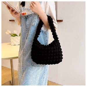 Dettaglio della trama a bolle nere della borsa hobo alla moda in morbida maglia