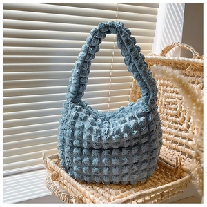 Dettaglio del tessuto popcorn azzurro su una piccola borsa a tracolla elegante e moderna