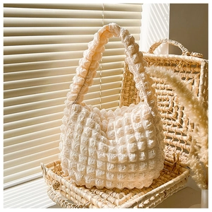 Dettaglio macro del tessuto a bolle color crema di questa borsa a spalla alla moda