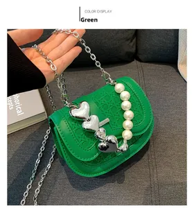 Detail van groene mini-tas met geweven textuur, zilveren hartgespen en parelmoeren handvat
