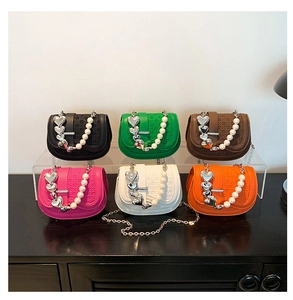 Mini crossbodytassen met parelhandvat in zes kleuren en hartbedeltjes op acryl display