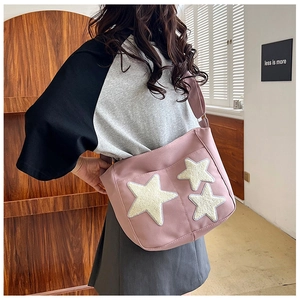 Pink canvas tote bag with star patches and adjustable strap shown on model in home setting