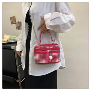 Détail du mini sac boîte rose vif avec clous argentés et chaîne porté par le mannequin