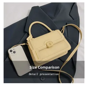 Vista detallada de un pequeño bolso bandolera de cuero PU beige junto a un móvil