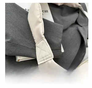 Detailed close-up showing reinforced X-shaped quilted stitching on beige nylon shoulder strap