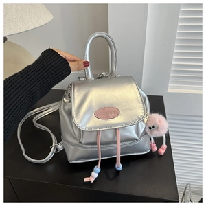 Primer plano de mini mochila plateada brillante con parche rosa y colgante de peluche