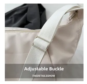 Close-up of the metal adjustable buckle and durable nylon strap on the beige shoulder bag