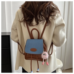 Detalle de mini mochila patchwork con solapa de tela vaquera azul y pompón rosa suave